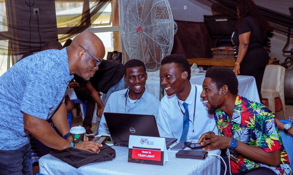 Mobolaji with a student team at an Innov8 hackathon table