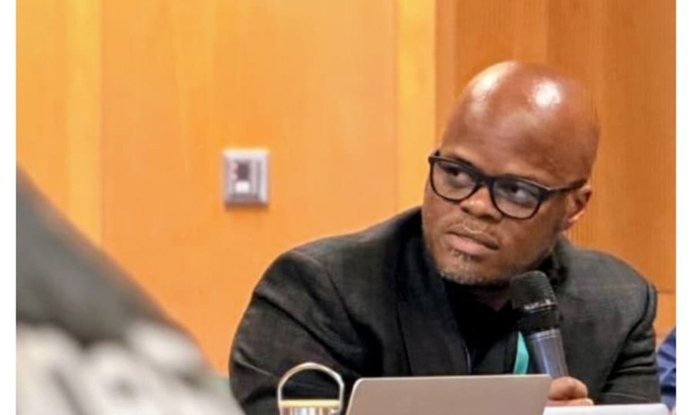 Mobolaji speaking into a microphone on a panel